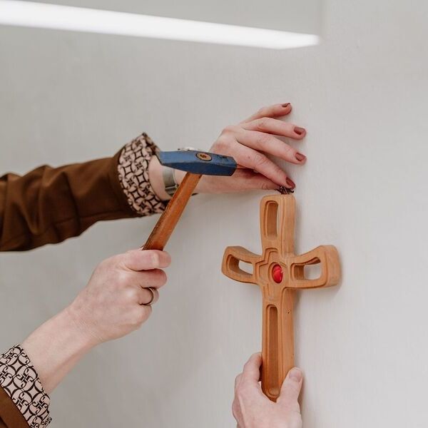 Ein hölzernes Kreuz wird an der Wand befestigt.