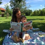 Im Obstgarten am Bauernhof ein Bauernhof-Buch lesen
